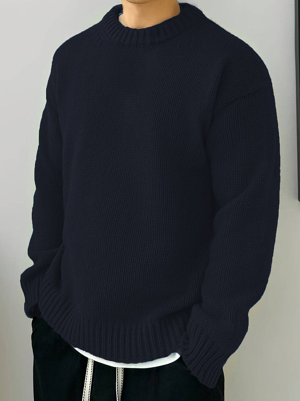 Zijaanzicht van een man die de zwarte heren sweater draagt, gecombineerd met een casual broek voor een complete look.