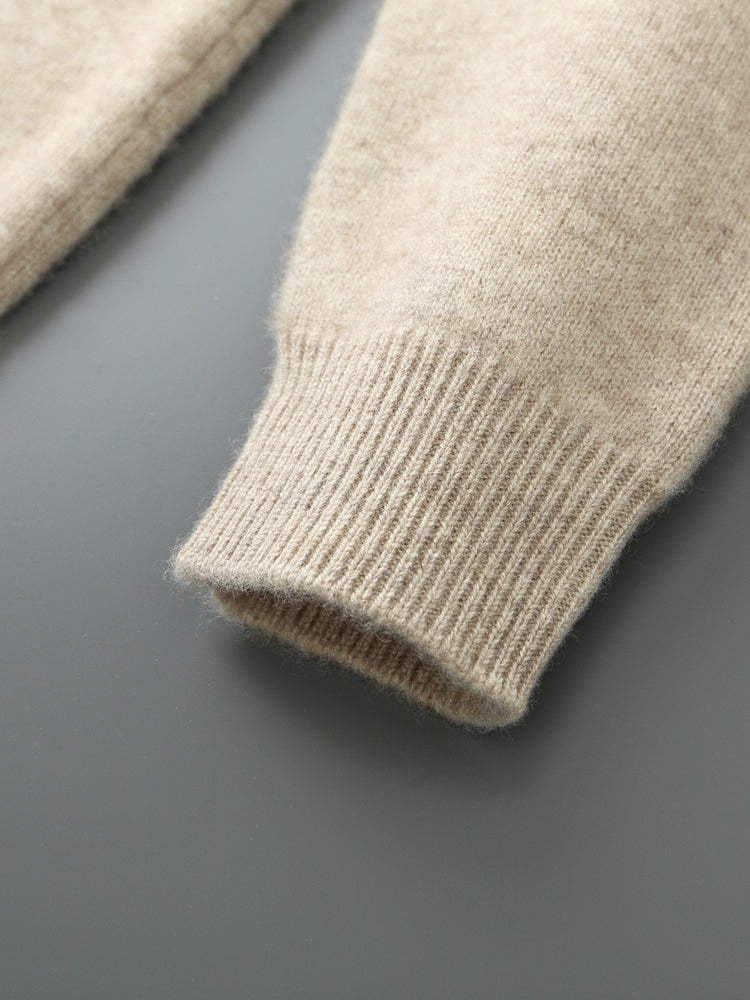 Detailopname van de ronde halslijn en de fijne brei van de beige Merino wollen sweater.