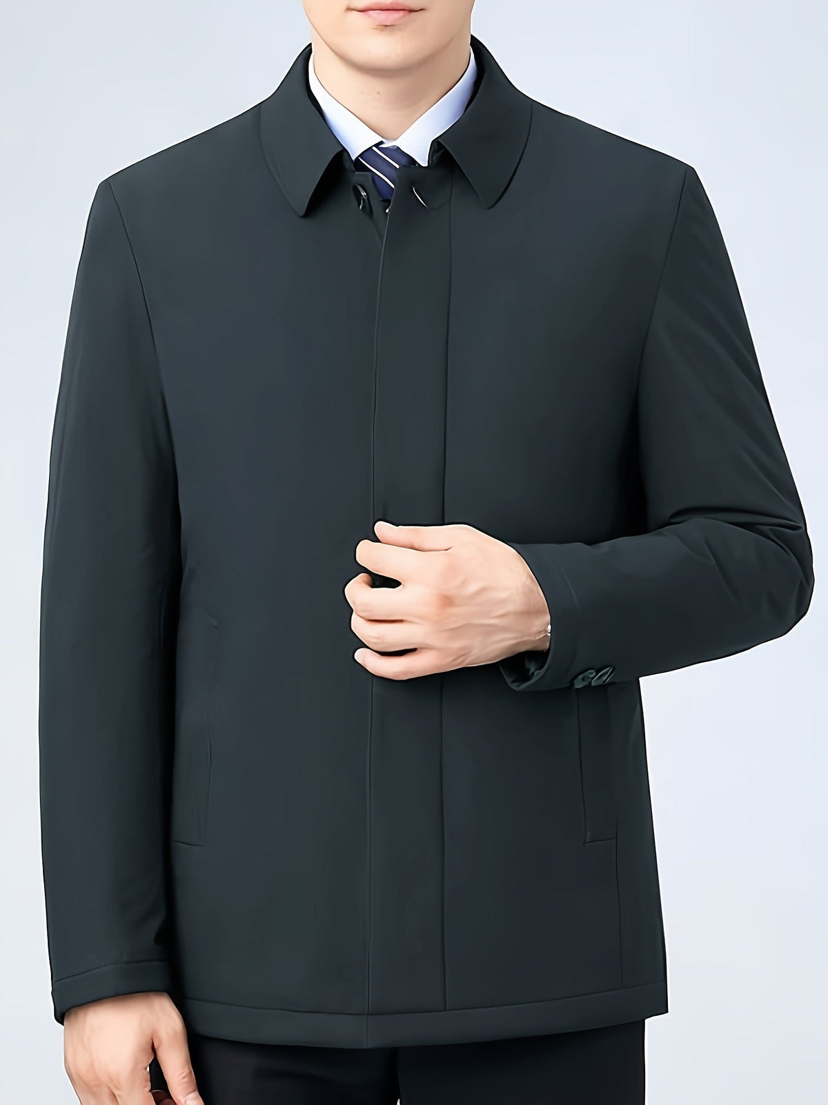 Man met de donkerblauwe jas aan, staand bij een raam, kijkend naar buiten.