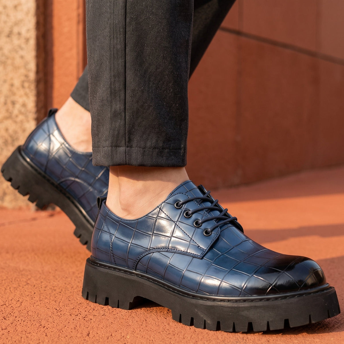 De blauwe leren derbyschoenen naast een pantalon, wat de veelzijdigheid van de schoen benadrukt.