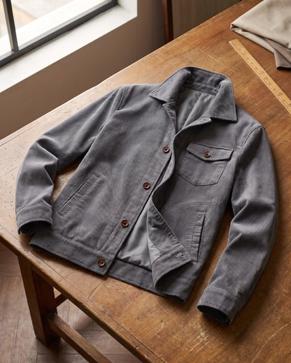 Een man zit comfortabel met de grijze corduroy jas aan, ideaal voor een relaxte dag.