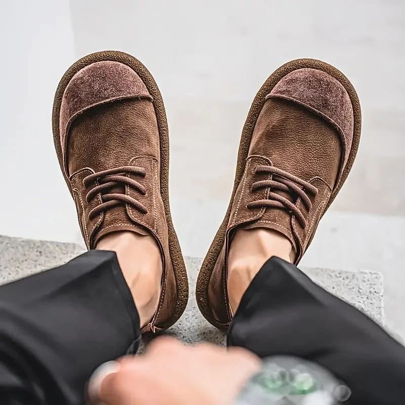 Een man die de Gideon lichtbruine schoenen aantrekt, waarbij de gemakkelijke instap wordt geïllustreerd.