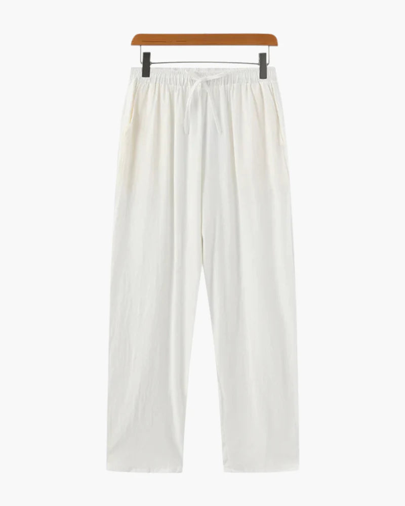 Een man draagt de witte linnen broek, staand in een ontspannen pose, wat de casual elegantie benadrukt.