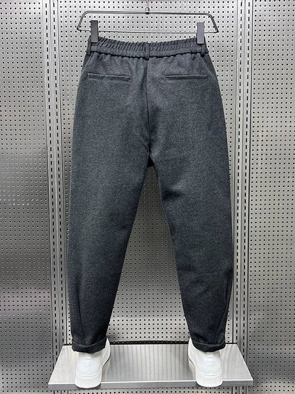 Benen van een model dat de zwarte broek draagt, met focus op de taps toelopende pijpen naar de enkel.