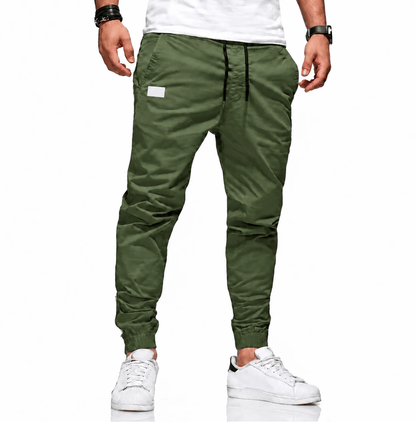 Man loopt casual in een groene cargobroek, dynamische pose die de bewegingsvrijheid van de broek benadrukt.