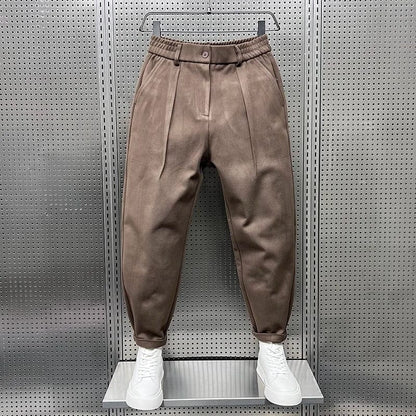 Zijaanzicht van de bruine taps toelopende broek, toont de elegante val van de stof en de pasvorm.