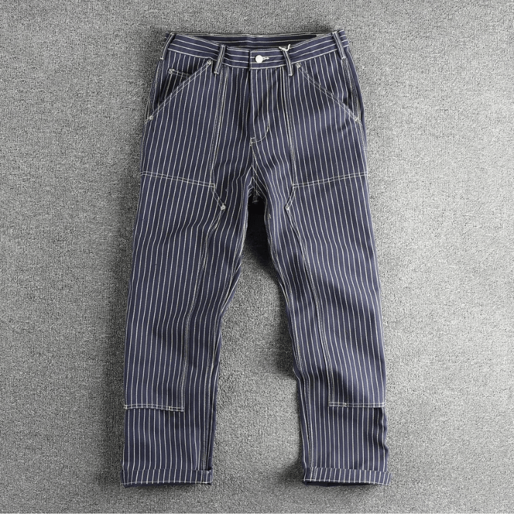 Detailopname van de versterkte dubbele kniepanelen op de kaki utility broek, met focus op de textuur van het katoen.