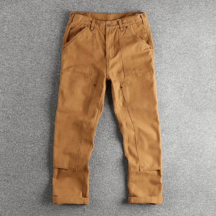 Zijaanzicht van de grijze utility broek, gedragen door een staande man, die de comfortabele pasvorm toont.