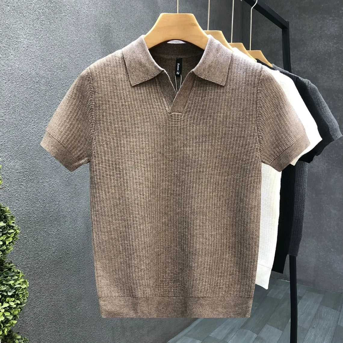 Het Jasper ademende gebreide poloshirt in het wit, plat gelegd om de stof en afwerking te benadrukken.