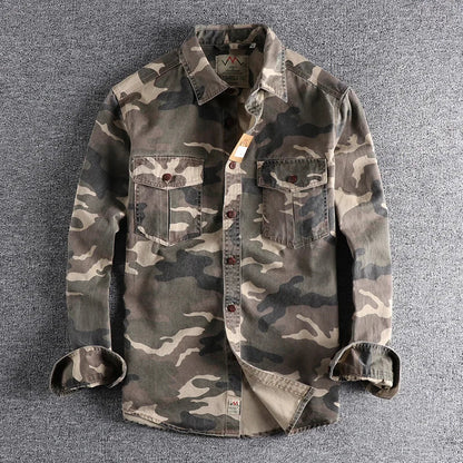 Detailopname van de stof van het camouflage T-shirt, waarbij de fijne textuur en het patroon goed zichtbaar zijn.