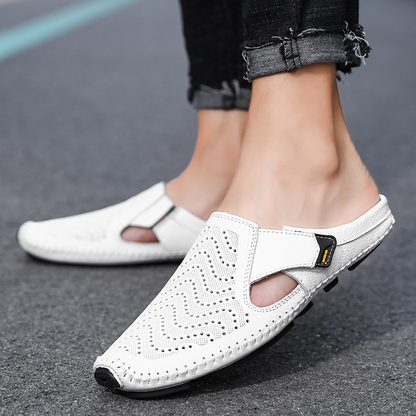 Een man zit ontspannen met zijn voeten in Julian leren sandalen, detail van het ademende ontwerp.
