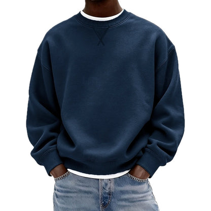 Man draagt de grijze katoenen sweater in een ontspannen houding, gecombineerd met een jeans voor een casual look.