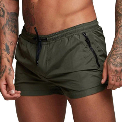Een man geniet van een strandwandeling met de groene Max zwemshort, illustreert het comfort en de bewegingsvrijheid die de zwemshort biedt.