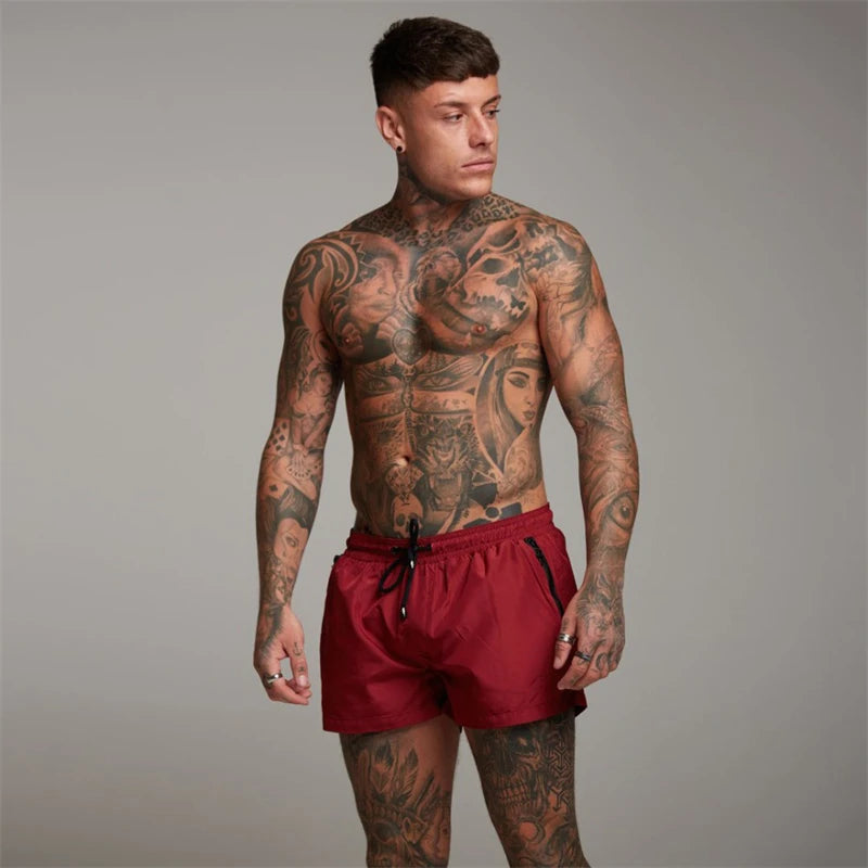 Een man draagt de Max zwemshort in marineblauw, staand bij het zwembad, toont de moderne pasvorm en lengte van de zwemshort.