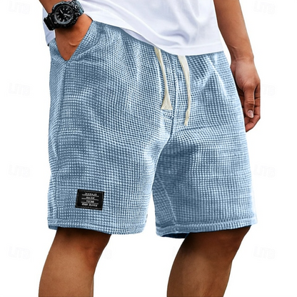 Close-up van de wafeltextuur op de stof van de beige shorts, die de ademende kwaliteit benadrukt.