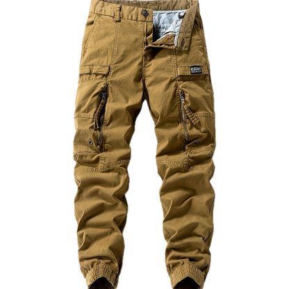 Een man in een bruine cargo jogger broek, staand in een stedelijke omgeving, toont de veelzijdigheid.
