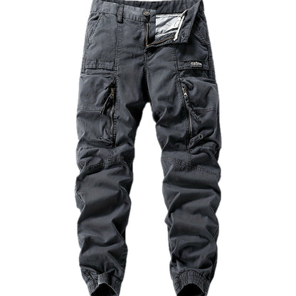 Zijaanzicht van de grijze cargo jogger broek gedragen door een man, gecombineerd met sneakers voor een casual look.